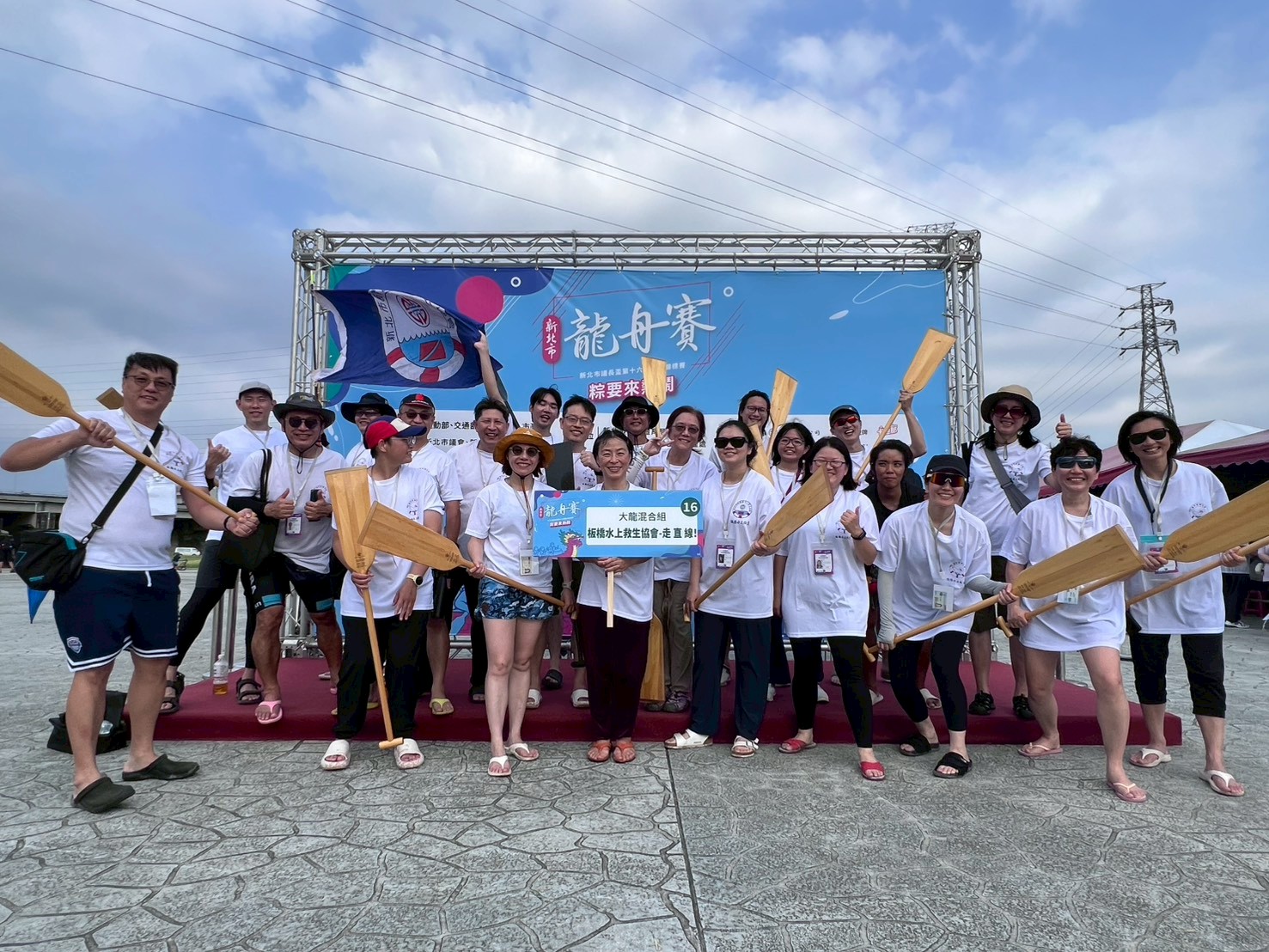 隊員在龍舟賽舞台前舉槳合影